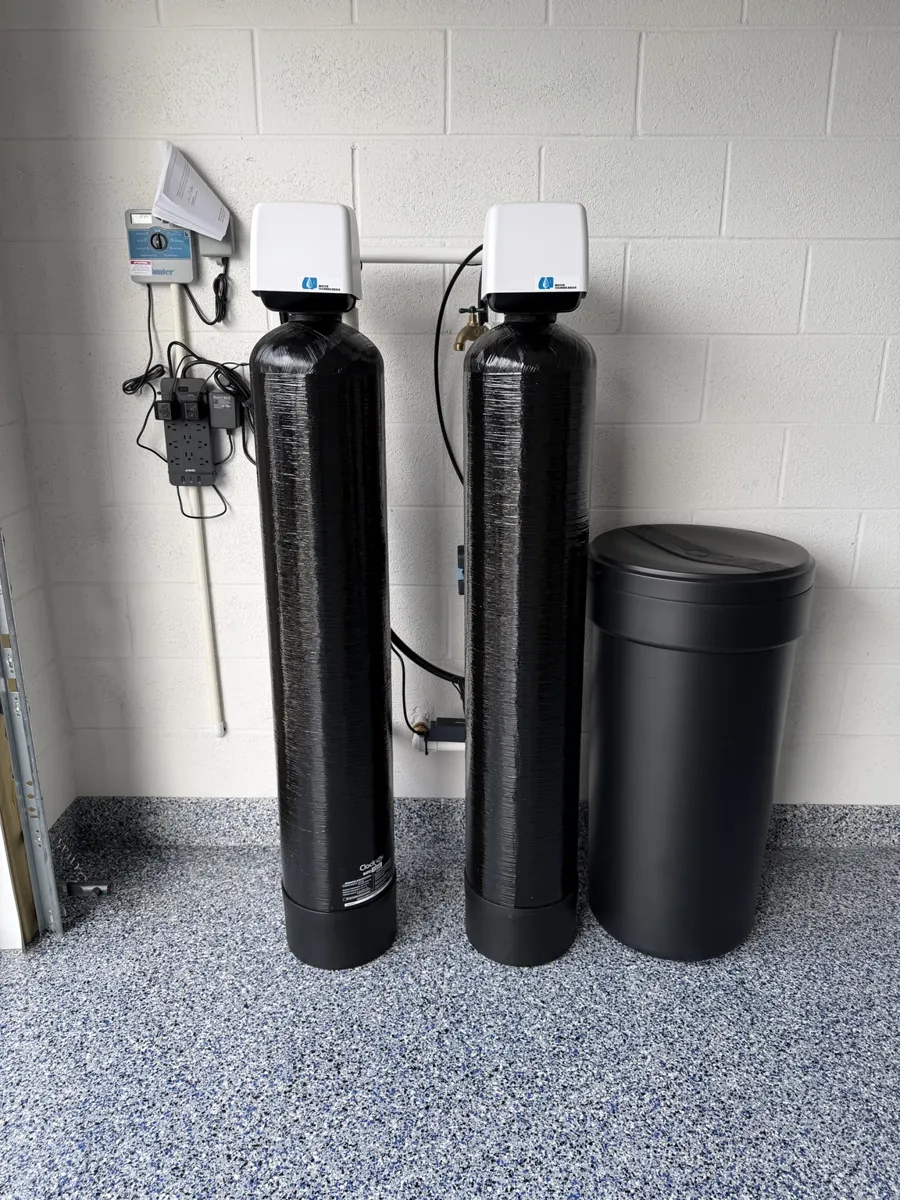 Black twin-tank softener system with brine tank installed in a garage